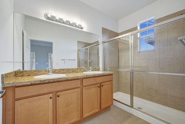full bath with tile patterned floors, a sink, a shower stall, and double vanity