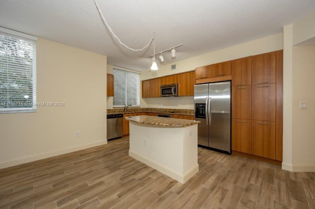 kitchen with a center island, sink, a textured ceiling, light hardwood / wood-style floors, and stainless steel appliances