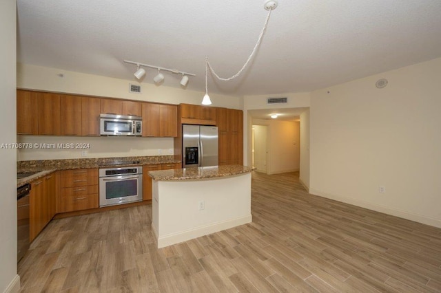 kitchen with appliances with stainless steel finishes, light hardwood / wood-style floors, a kitchen island, and stone countertops