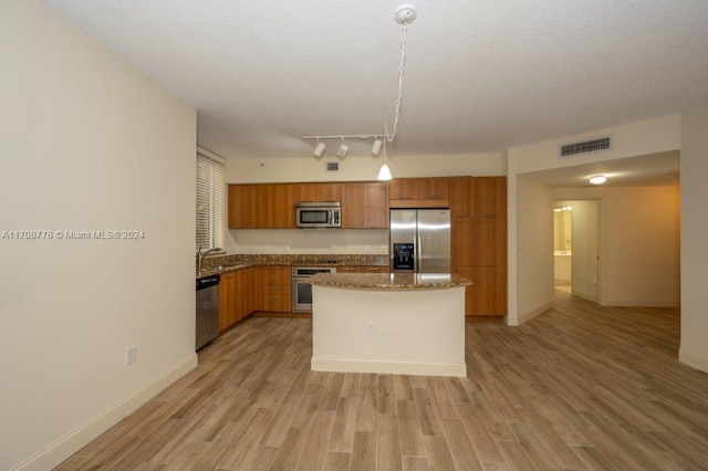 kitchen with sink, light wood-type flooring, decorative light fixtures, a kitchen island, and stainless steel appliances