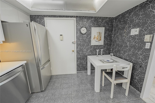 kitchen with stainless steel dishwasher, refrigerator, and white cabinetry