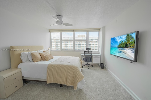 bedroom with ceiling fan, light carpet, and a textured ceiling