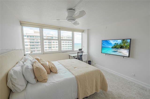 carpeted bedroom with a water view, a textured ceiling, and multiple windows