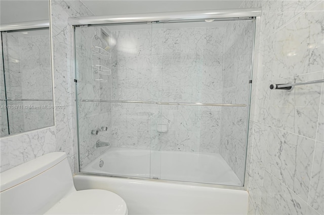 bathroom with enclosed tub / shower combo, tile walls, and toilet