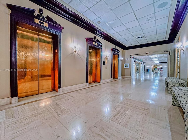 corridor with a drop ceiling, ornamental molding, and elevator