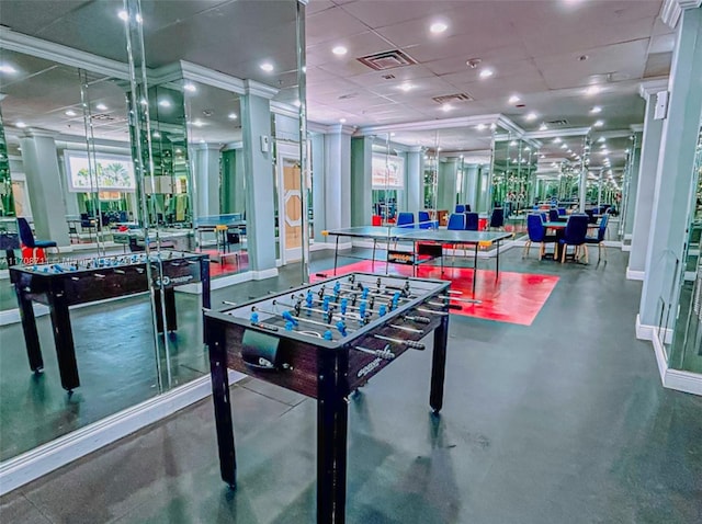 game room with concrete flooring, a paneled ceiling, plenty of natural light, and ornamental molding