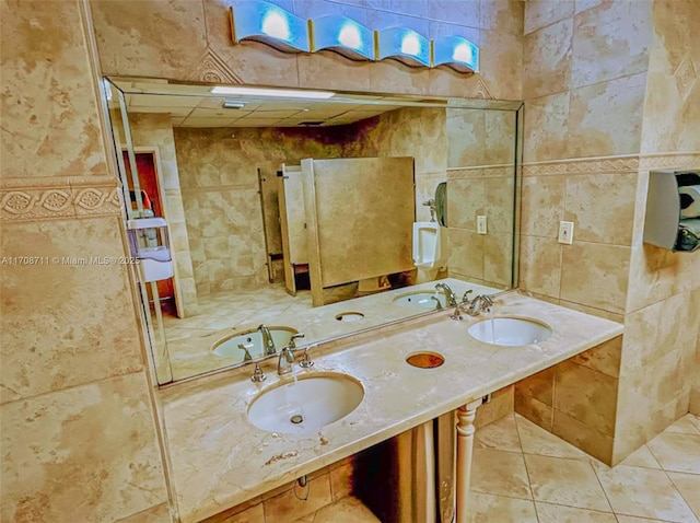 bathroom featuring tile patterned floors, tile walls, and double sink