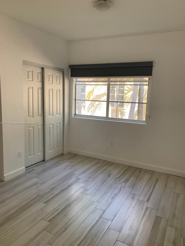 unfurnished bedroom with light hardwood / wood-style floors and a closet