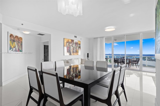 dining space with light tile patterned flooring, a water view, floor to ceiling windows, and an inviting chandelier