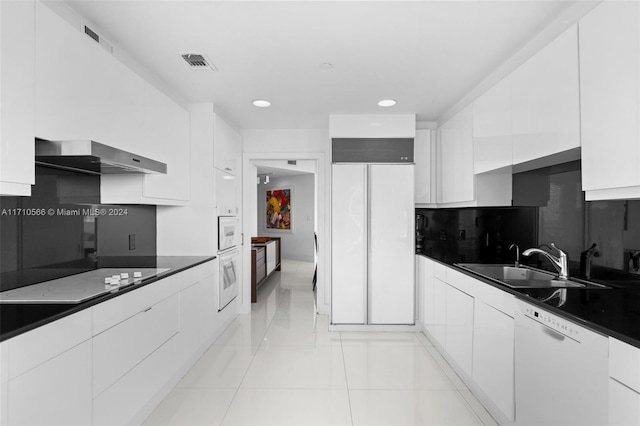 kitchen with wall chimney range hood, sink, white cabinets, and white appliances