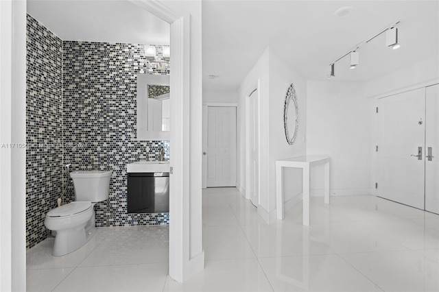 bathroom with tile patterned floors, sink, tile walls, and toilet