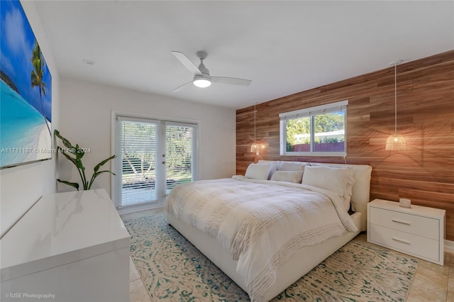 tiled bedroom featuring access to exterior, wooden walls, and ceiling fan