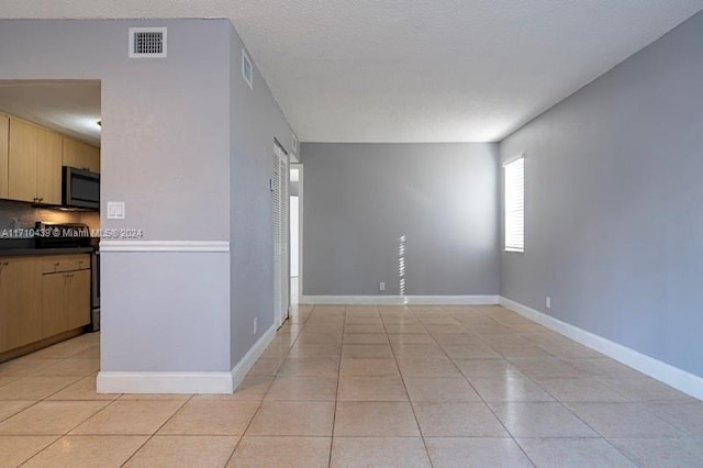 interior space featuring light tile patterned floors, range with electric stovetop, decorative backsplash, and light brown cabinets