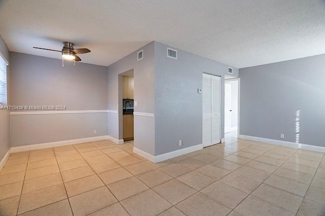 empty room featuring light tile patterned flooring, ceiling fan, and a textured ceiling