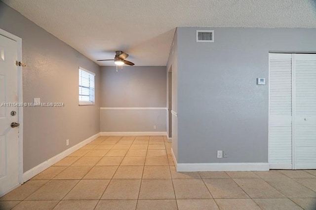 empty room with light tile patterned flooring, ceiling fan, and a textured ceiling