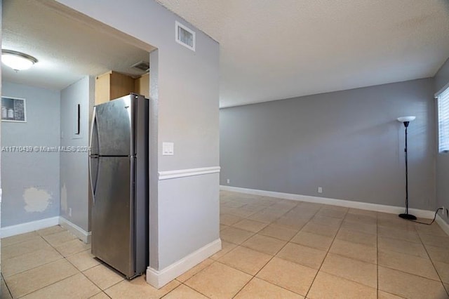 kitchen with stainless steel fridge, a textured ceiling, and light tile patterned floors