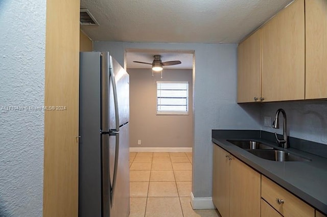 kitchen featuring light tile patterned flooring, sink, light brown cabinets, stainless steel refrigerator, and ceiling fan