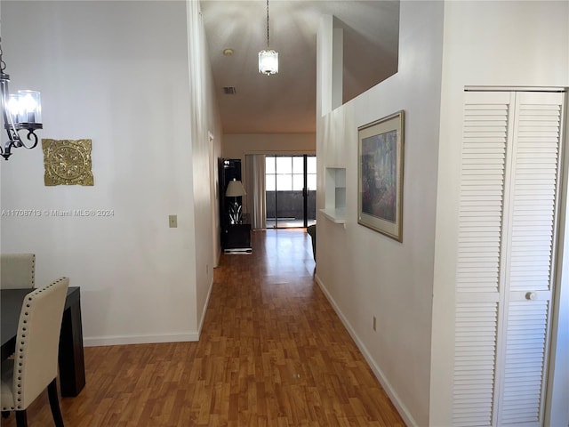 hallway with a towering ceiling, dark wood-type flooring, and an inviting chandelier