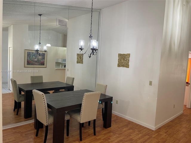 dining space with a chandelier, wood-type flooring, and vaulted ceiling