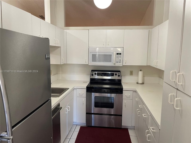 kitchen featuring appliances with stainless steel finishes, light tile patterned floors, white cabinetry, and sink