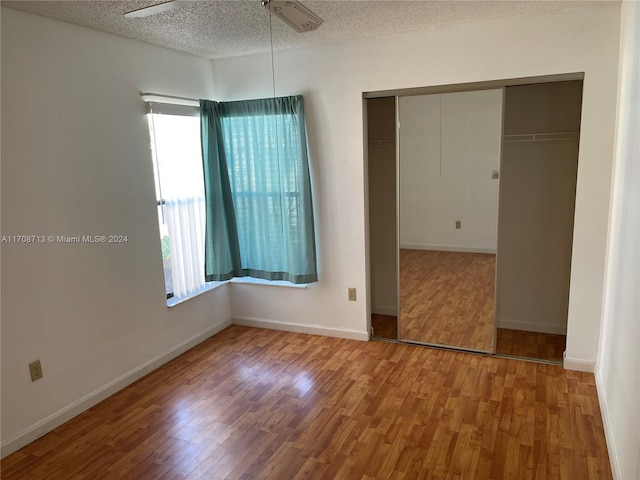 unfurnished bedroom with hardwood / wood-style floors, a textured ceiling, a closet, and ceiling fan