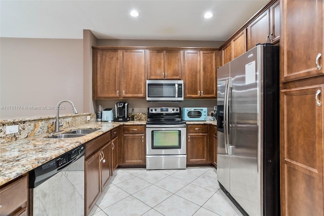 kitchen with light tile patterned flooring, sink, kitchen peninsula, stainless steel appliances, and light stone countertops