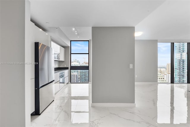 kitchen featuring floor to ceiling windows, white cabinetry, rail lighting, and stainless steel appliances