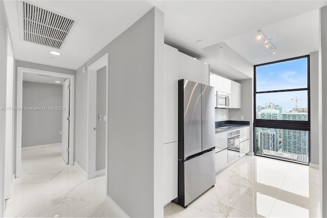 kitchen featuring appliances with stainless steel finishes, white cabinetry, and floor to ceiling windows