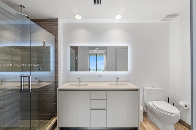 bathroom featuring wood-type flooring, vanity, toilet, and a shower with door