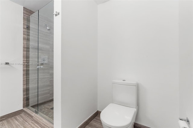 bathroom with hardwood / wood-style floors, toilet, and an enclosed shower