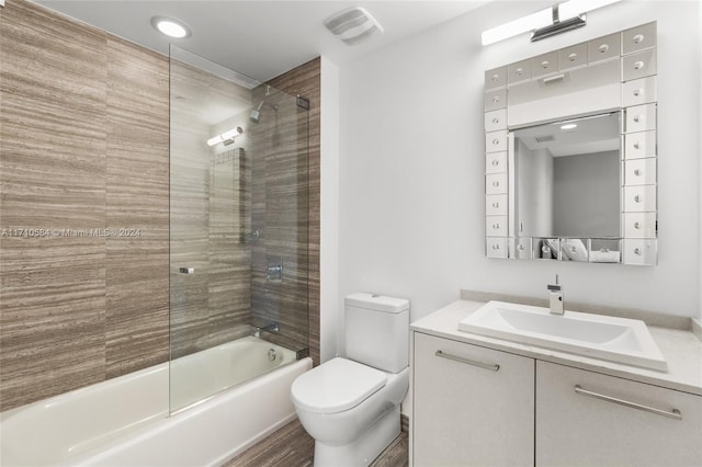 full bathroom with hardwood / wood-style flooring, tiled shower / bath combo, toilet, and vanity