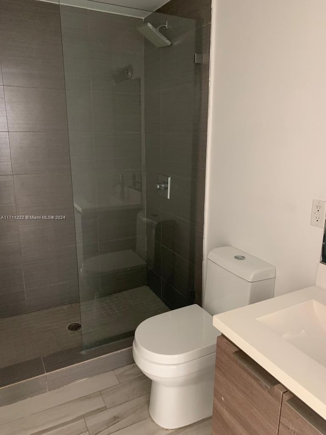 bathroom featuring vanity, toilet, and tiled shower