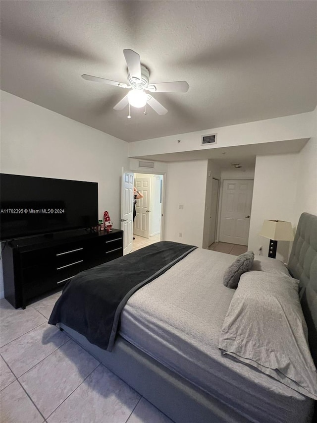 bedroom with ceiling fan, light tile patterned floors, and a textured ceiling