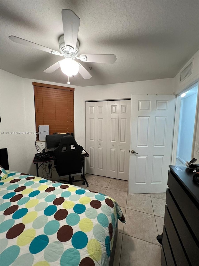 bedroom featuring ceiling fan, light tile patterned flooring, a textured ceiling, and a closet