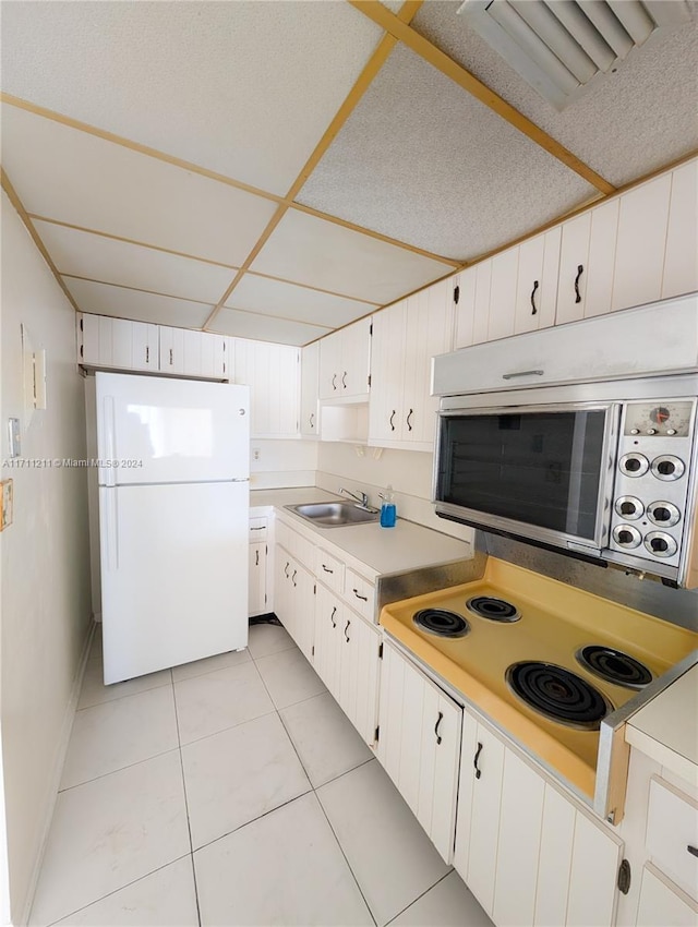 kitchen with electric stovetop, white refrigerator, white cabinetry, and sink