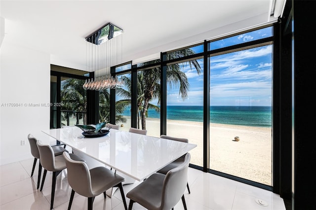 dining area with light tile patterned floors, a water view, and a beach view