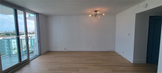 spare room with light wood-type flooring, expansive windows, and a chandelier