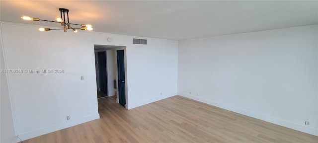 empty room featuring light wood-type flooring and a chandelier