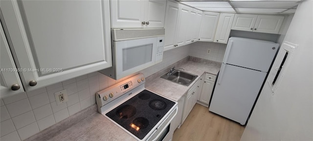 kitchen featuring sink, white appliances, white cabinets, and decorative backsplash