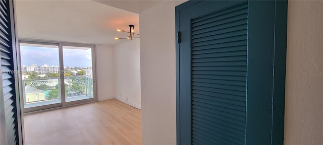 spare room with light hardwood / wood-style flooring, floor to ceiling windows, and a notable chandelier