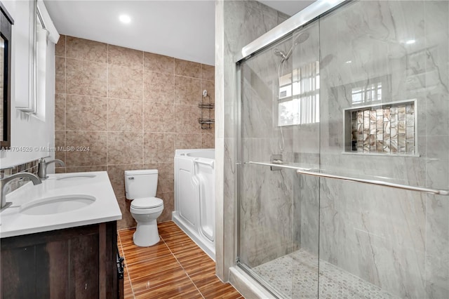 bathroom featuring vanity, a shower with door, toilet, and tile walls