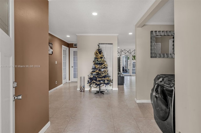 corridor featuring french doors, a textured ceiling, light tile patterned floors, washer and dryer, and ornamental molding