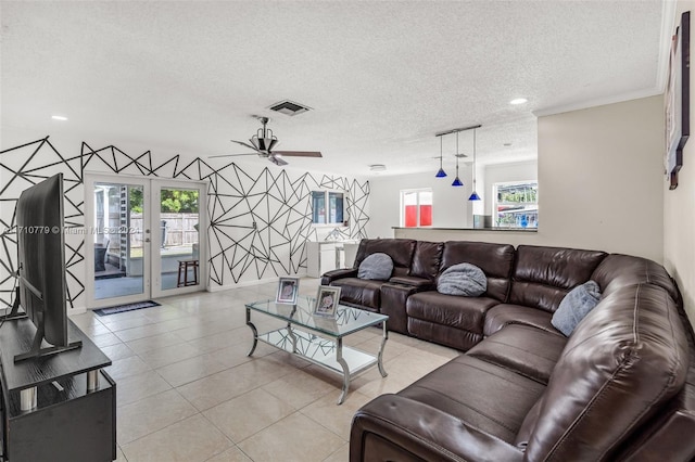 living room featuring plenty of natural light, ceiling fan, light tile patterned floors, and a textured ceiling