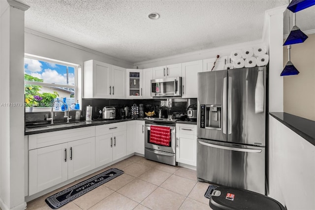 kitchen with appliances with stainless steel finishes, white cabinetry, ornamental molding, and sink