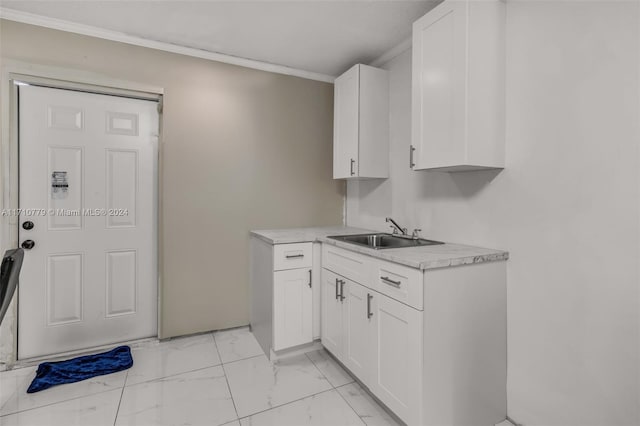 kitchen featuring white cabinetry, ornamental molding, and sink