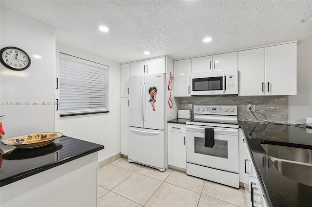 kitchen featuring tasteful backsplash, a textured ceiling, white appliances, white cabinetry, and light tile patterned flooring