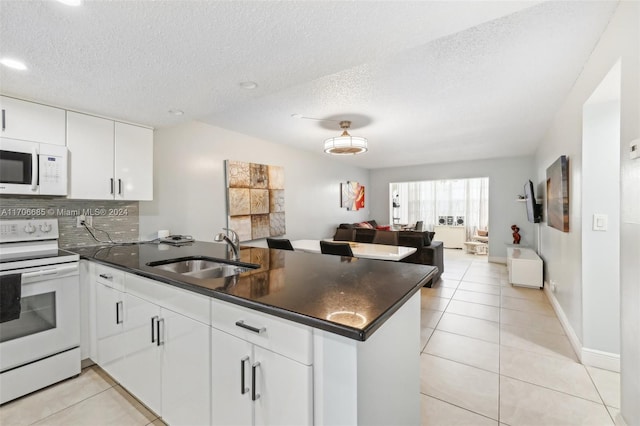 kitchen with white appliances, white cabinets, sink, a textured ceiling, and kitchen peninsula