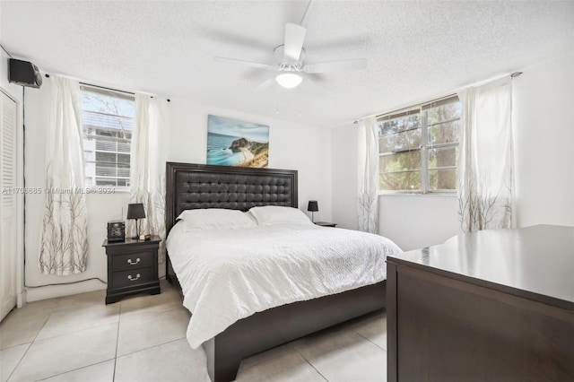 bedroom with a textured ceiling, ceiling fan, and light tile patterned flooring