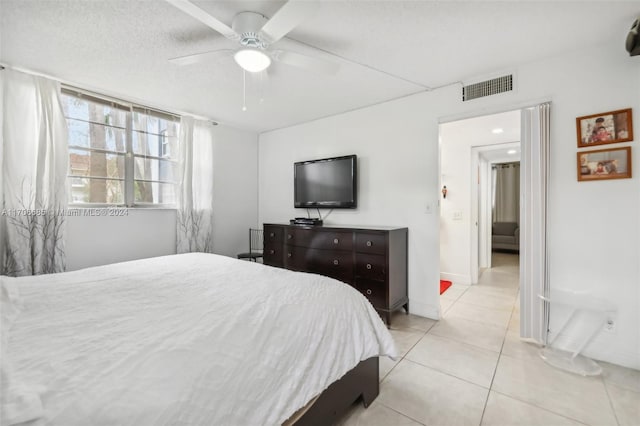 tiled bedroom with ceiling fan and a textured ceiling