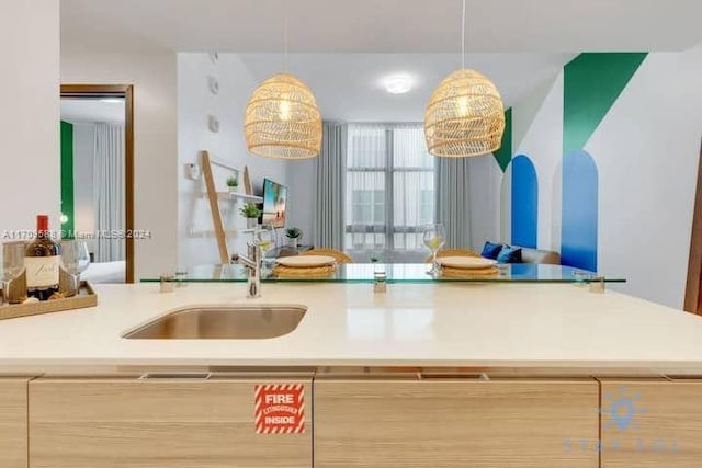 kitchen with light brown cabinetry, sink, and pendant lighting